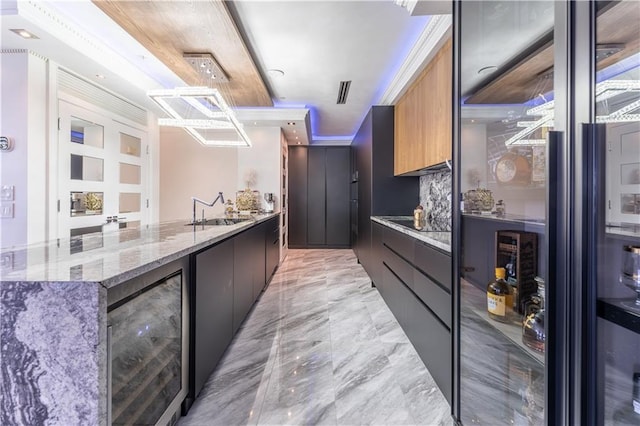 kitchen featuring sink, beverage cooler, light stone counters, decorative backsplash, and ornamental molding