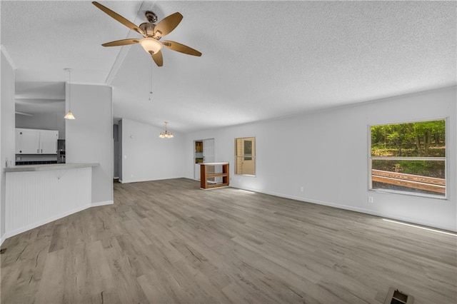 1437 Frank Lovell Rd, Clarkesville, GA 30523 - unfurnished living room featuring a textured ceiling, vaulted ceiling, wood finished floors, baseboards, and ceiling fan with notable chandelier