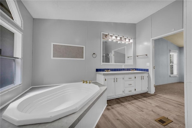 1437 Frank Lovell Rd, Clarkesville, GA 30523 - bathroom with visible vents, double vanity, wood finished floors, a bath, and a sink