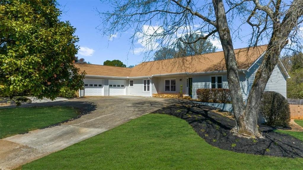 ranch-style house featuring a garage, concrete driveway, fence, and a front yard