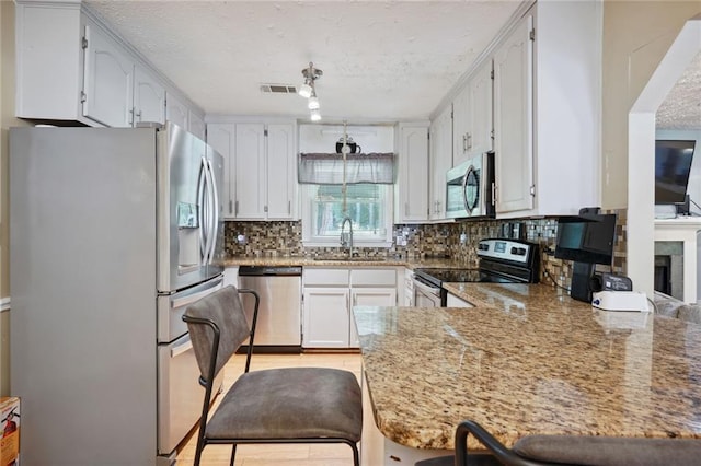 kitchen with kitchen peninsula, light stone countertops, sink, and stainless steel appliances