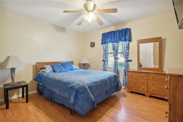 bedroom with ceiling fan, light hardwood / wood-style floors, and a textured ceiling