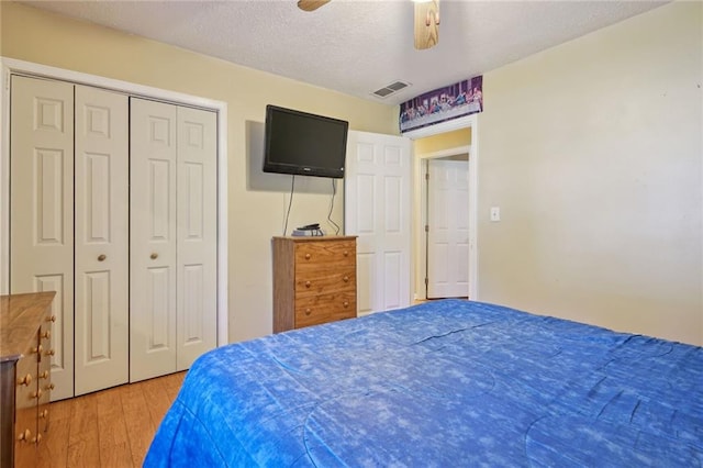 bedroom featuring ceiling fan, a closet, wood-type flooring, and a textured ceiling