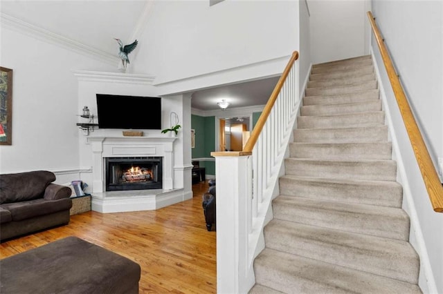 stairway featuring wood-type flooring and crown molding