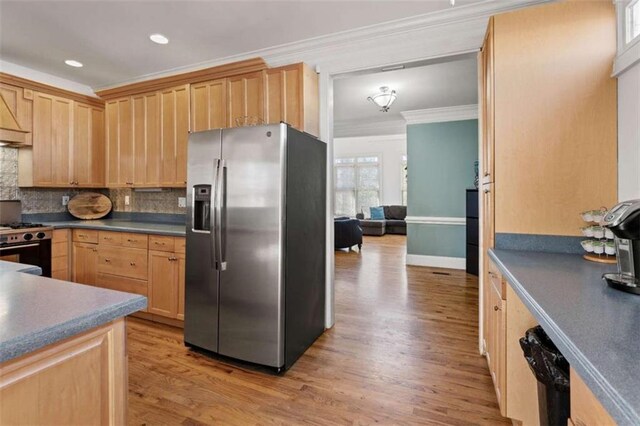 kitchen featuring appliances with stainless steel finishes, tasteful backsplash, crown molding, light brown cabinets, and light hardwood / wood-style flooring