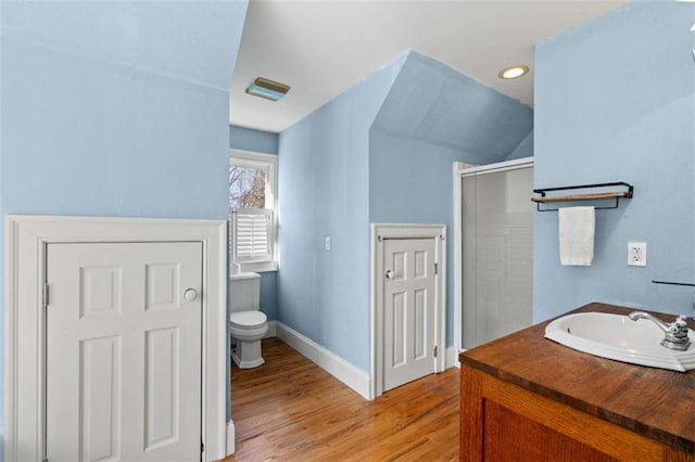 bathroom featuring wood-type flooring, vanity, toilet, and a shower with shower door