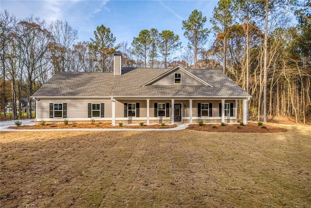 view of front of house featuring a porch, roof with shingles, a chimney, and a front lawn