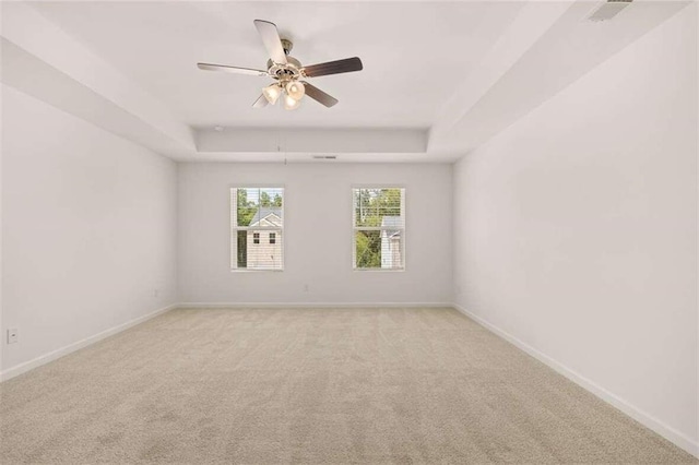 spare room featuring baseboards, a raised ceiling, light colored carpet, and ceiling fan