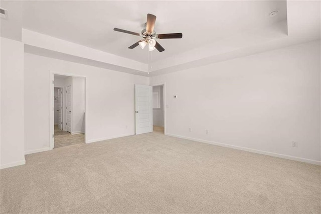 unfurnished bedroom featuring a tray ceiling, visible vents, baseboards, and light carpet