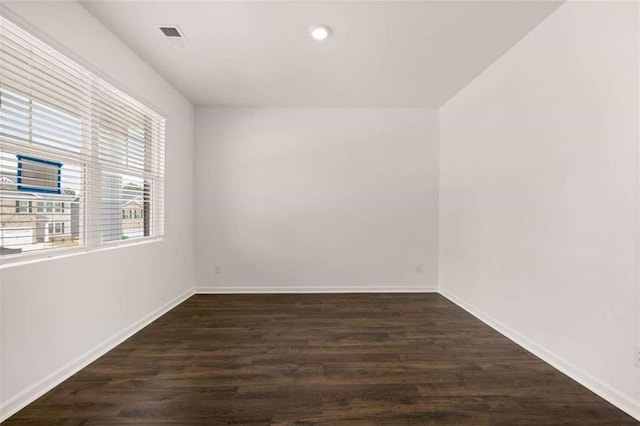 unfurnished room featuring visible vents, dark wood-style floors, and baseboards