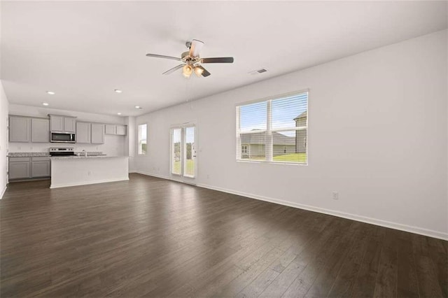 unfurnished living room featuring a ceiling fan, visible vents, baseboards, recessed lighting, and dark wood-style flooring