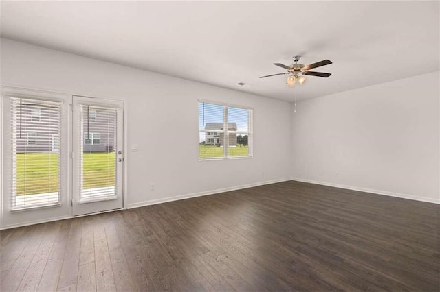 spare room featuring baseboards, dark wood-style floors, and a ceiling fan