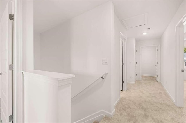hall with baseboards, an upstairs landing, and light colored carpet
