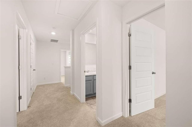 corridor with visible vents, baseboards, and light colored carpet