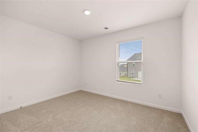spare room featuring baseboards and light carpet