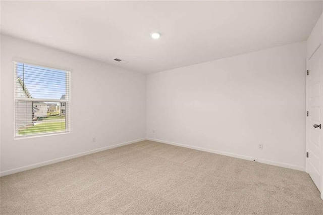 empty room featuring visible vents, light colored carpet, and baseboards