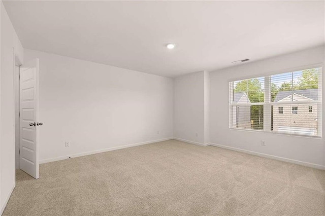 empty room with visible vents, light colored carpet, and baseboards