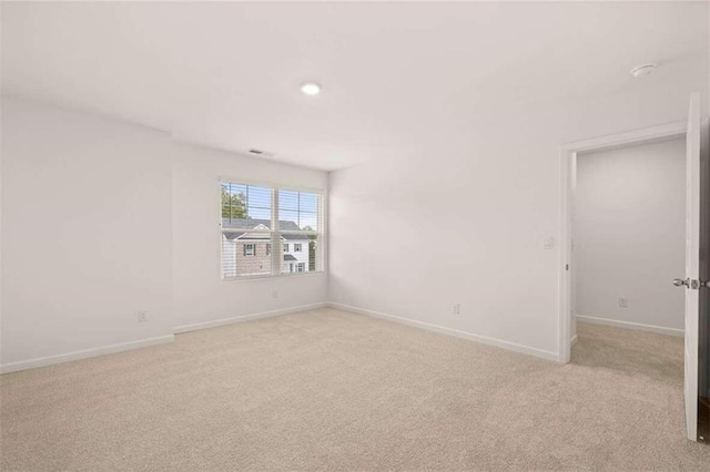 empty room featuring baseboards and light carpet