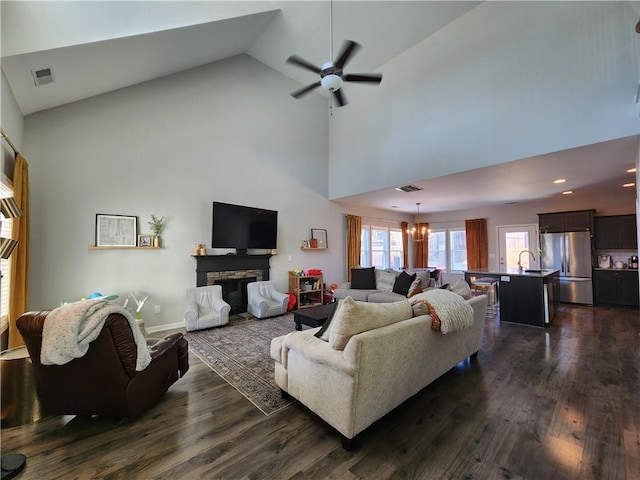 living area with dark wood-style floors, a stone fireplace, and plenty of natural light