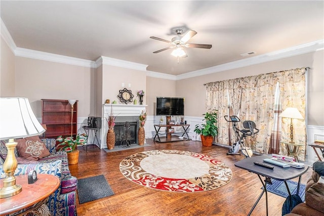 living area featuring visible vents, a fireplace with flush hearth, wood finished floors, and a wainscoted wall