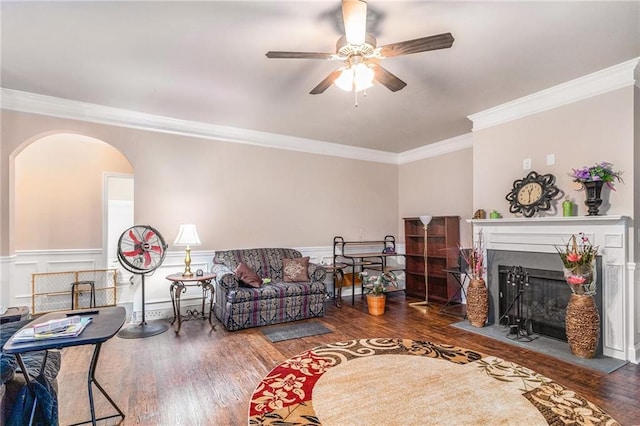 living area featuring wainscoting, a fireplace, ornamental molding, and wood finished floors