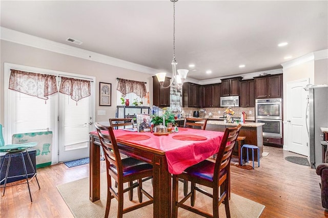 dining area featuring visible vents, ornamental molding, recessed lighting, light wood-style flooring, and an inviting chandelier