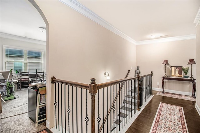 hallway featuring baseboards, ornamental molding, an upstairs landing, wood finished floors, and arched walkways