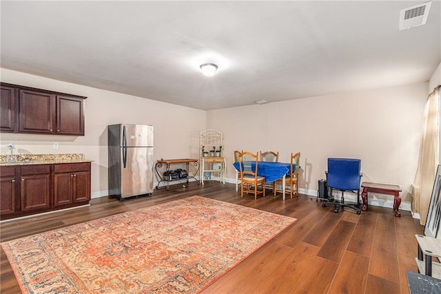 interior space with dark wood finished floors, visible vents, freestanding refrigerator, and a sink