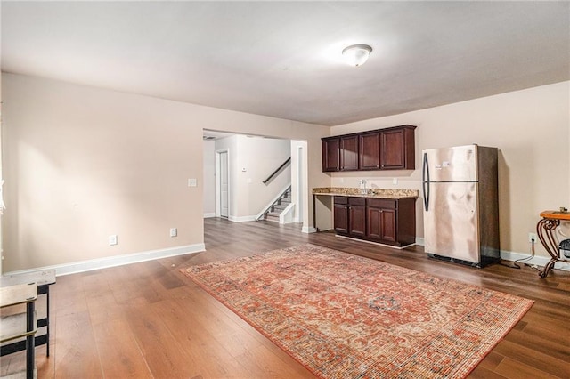 kitchen featuring dark wood finished floors, light countertops, dark brown cabinets, and freestanding refrigerator