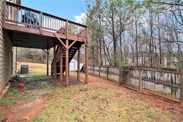 view of yard with stairs, a storage shed, a deck, a fenced backyard, and an outbuilding