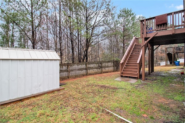 view of yard featuring fence, a storage shed, an outdoor structure, a wooden deck, and stairs