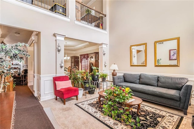 living room featuring visible vents, a wainscoted wall, ornamental molding, carpet flooring, and ornate columns