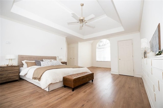 200 Ridge Bluff Ln, Suwanee, GA 30024 - bedroom featuring a tray ceiling, light wood finished floors, a ceiling fan, and ornamental molding
