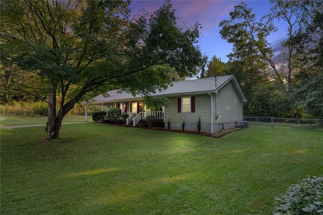 property exterior at dusk with covered porch and a lawn