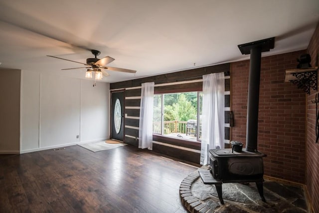 1530 Unity Church Cir, Maysville, GA 30558 - unfurnished living room featuring a wood stove, dark wood-style flooring, a ceiling fan, and brick wall