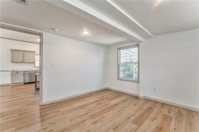 spare room featuring a wealth of natural light, baseboards, and light wood-style floors