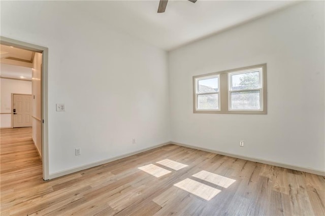 spare room with baseboards, light wood-style floors, and a ceiling fan