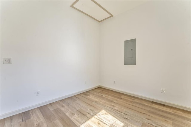 unfurnished room featuring electric panel, light wood-type flooring, and baseboards