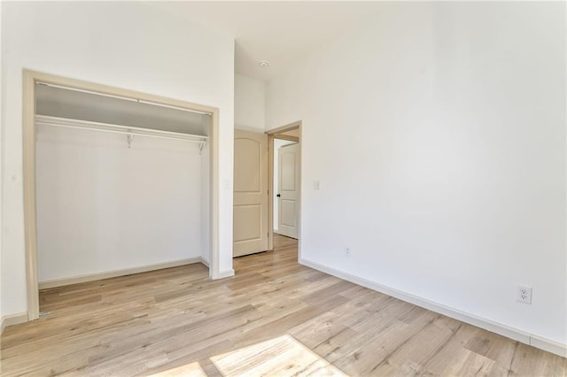 unfurnished bedroom with a closet, baseboards, and light wood finished floors