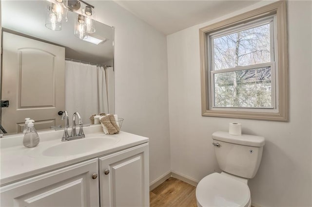 bathroom with baseboards, toilet, wood finished floors, and vanity