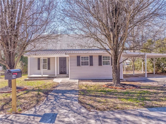 single story home with metal roof, a carport, a porch, and driveway