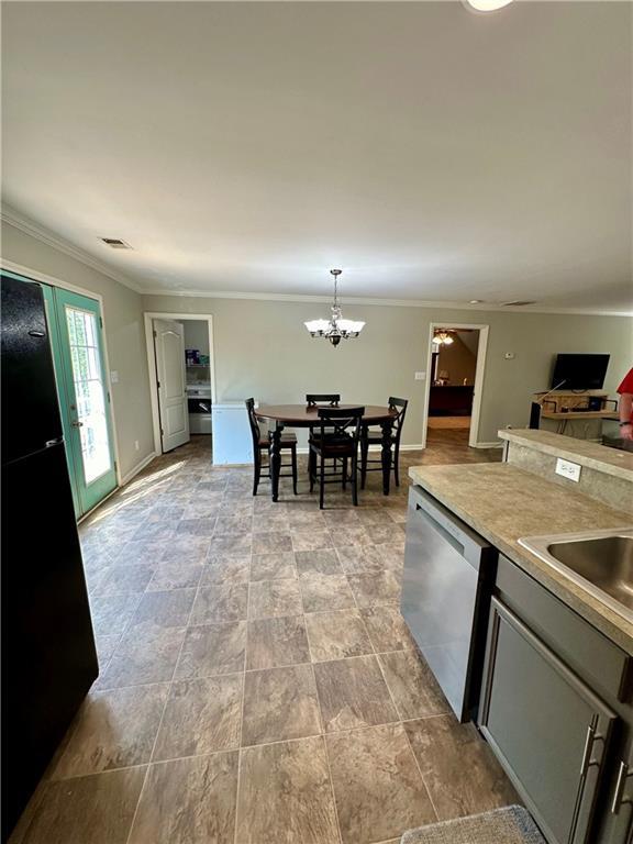 kitchen with black fridge, stainless steel dishwasher, a chandelier, decorative light fixtures, and ornamental molding