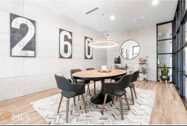 dining room featuring light wood-type flooring and tile walls