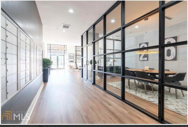 corridor with floor to ceiling windows, wood-type flooring, and a mail area