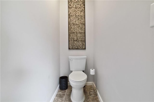 bathroom with baseboards, tile patterned flooring, and toilet