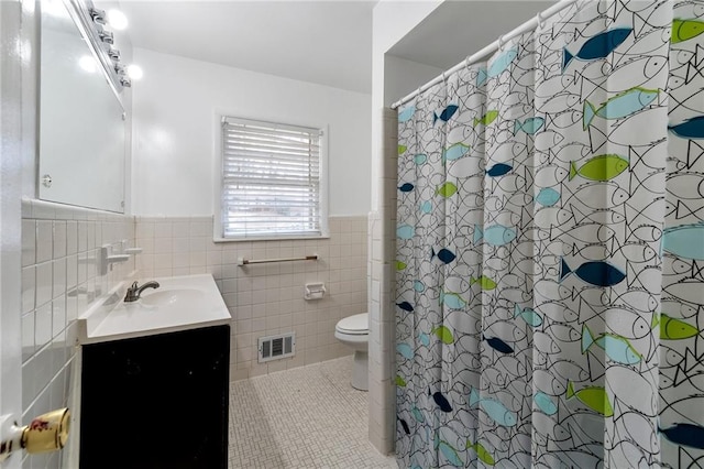 bathroom with curtained shower, tile walls, toilet, and vanity