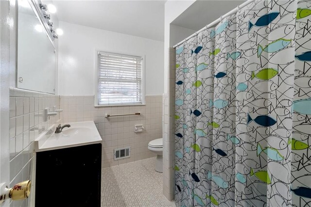 bathroom featuring tile walls, a shower with curtain, toilet, and vanity