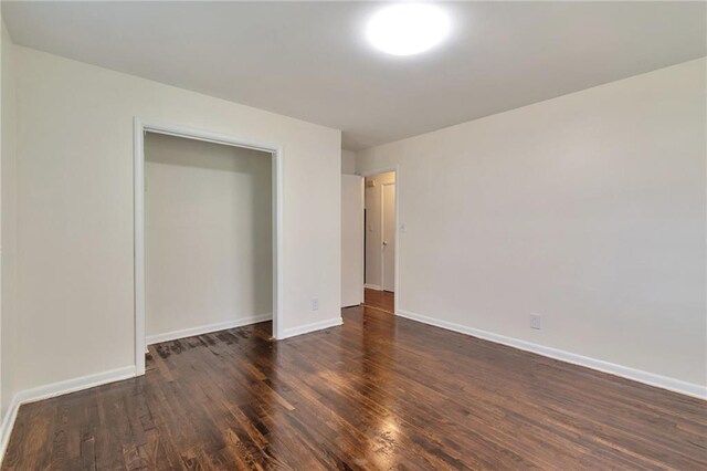 unfurnished bedroom with dark hardwood / wood-style floors and a closet