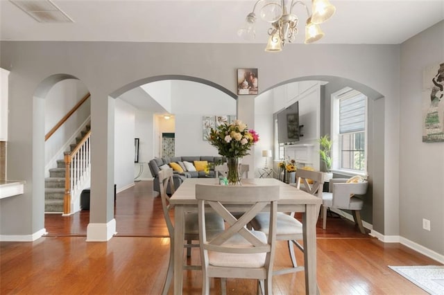 829 Castlebottom Dr, Lawrenceville, GA 30045 - dining space with light wood finished floors, arched walkways, a chandelier, and stairs