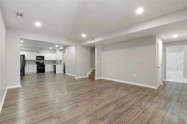 829 Castlebottom Dr, Lawrenceville, GA 30045 - unfurnished living room with stairway, baseboards, recessed lighting, and wood finished floors